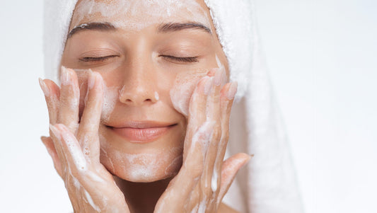 Donna con pelle luminosa mentre applica la mousse detergente sul viso come parte della skincare viso mattutina