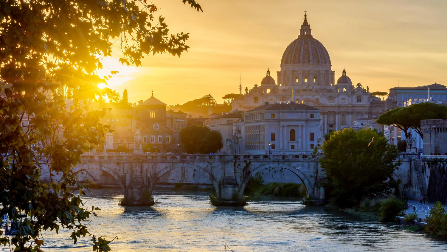 Veduta al tramonto della Basilica di San Pietro e del ponte sul fiume Tevere a Roma